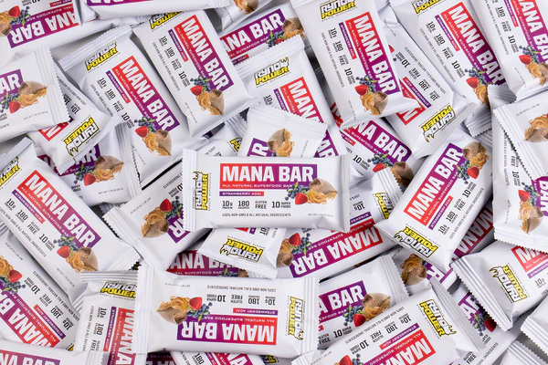 Varios paquetes de Strawberry Acai Mana Bar apilados uno sobre otro.